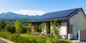 熊本県の山並みを背景に太陽光パネルと家庭用蓄電池を備えた戸建住宅